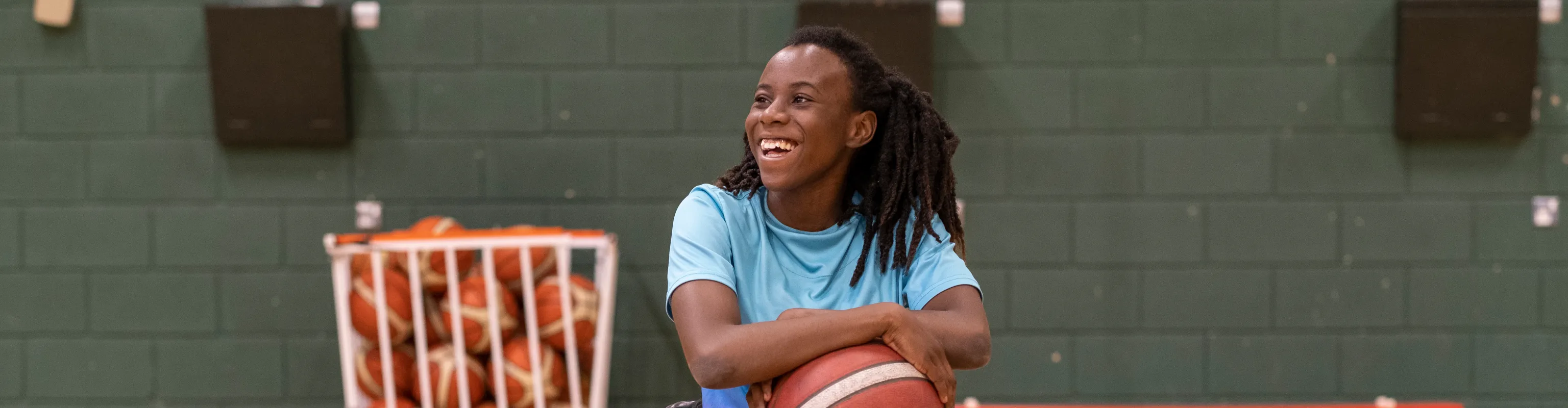 Woman in a wheelchair smiling and holding a basketball