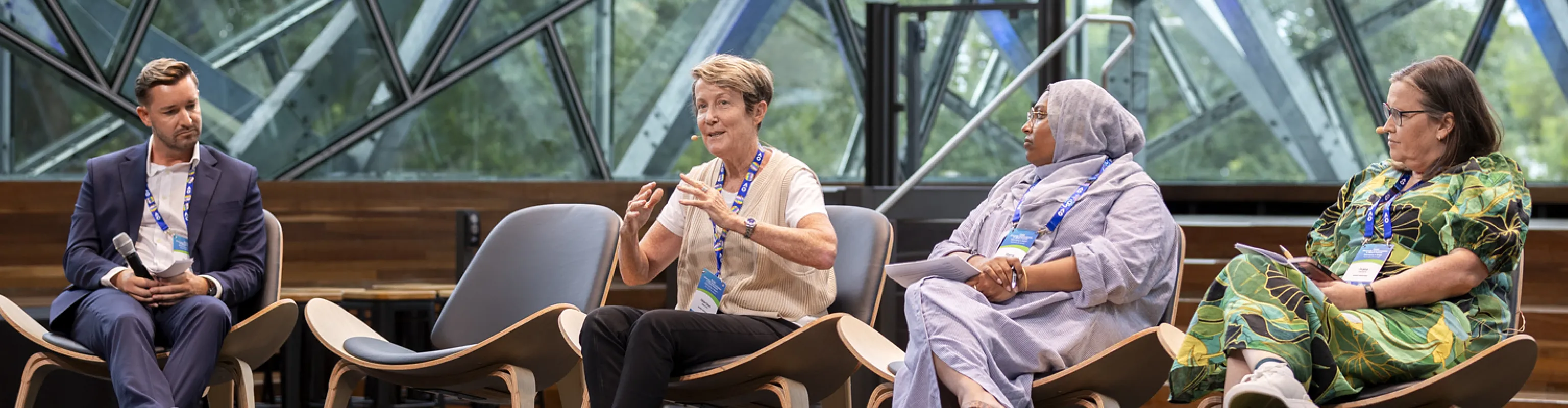 One man and three women take part in a panel discussino on a stage