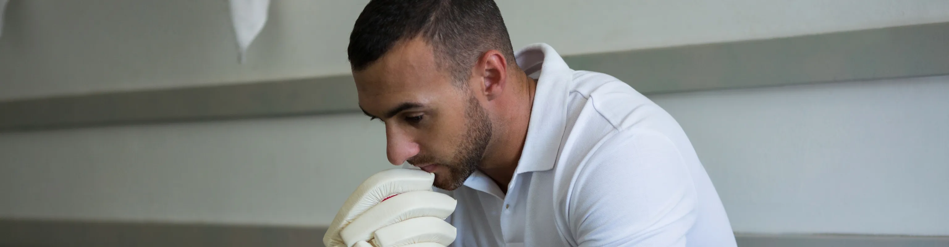 Man in cricket gear sitting in change rooms