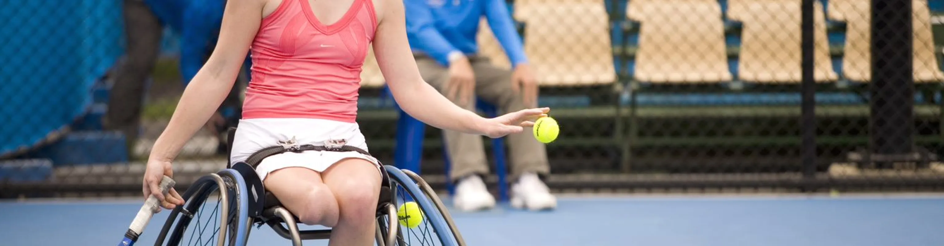 Woman in wheelchair serving a tennis ball