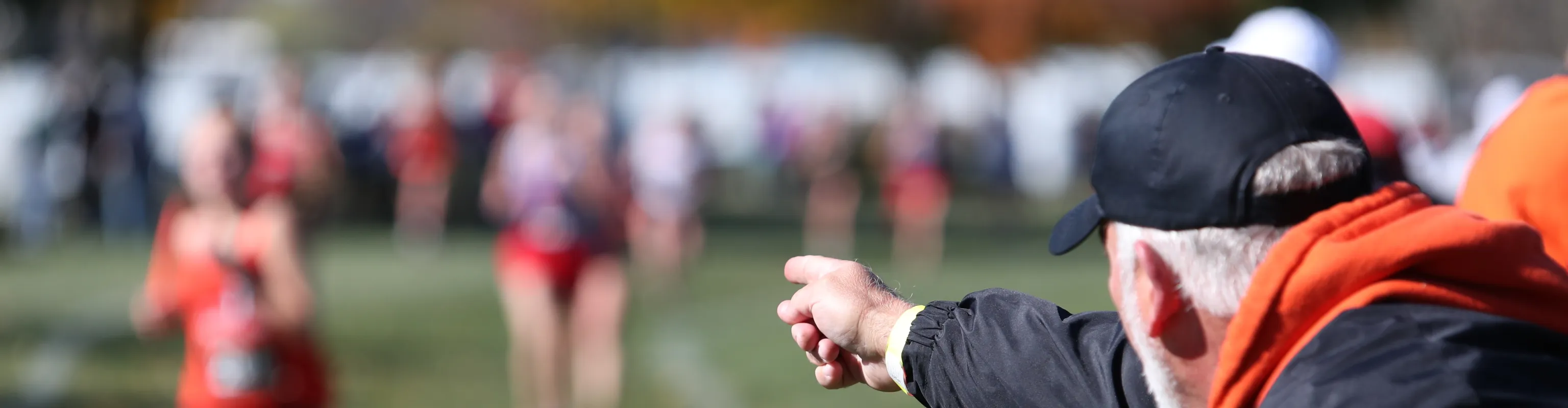 Man pointing at young athlete running