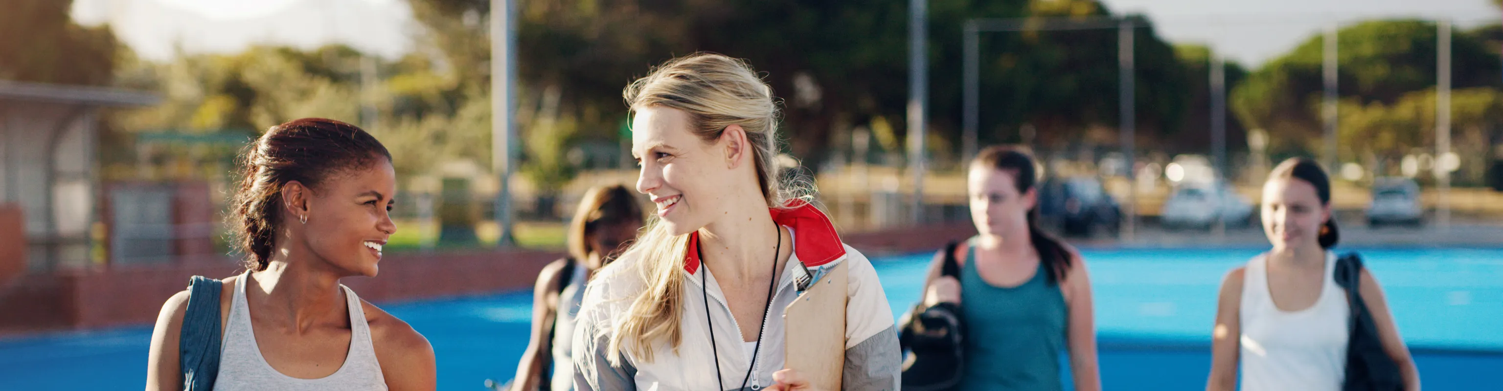Smiling field hockey players walk with their coach after a training session