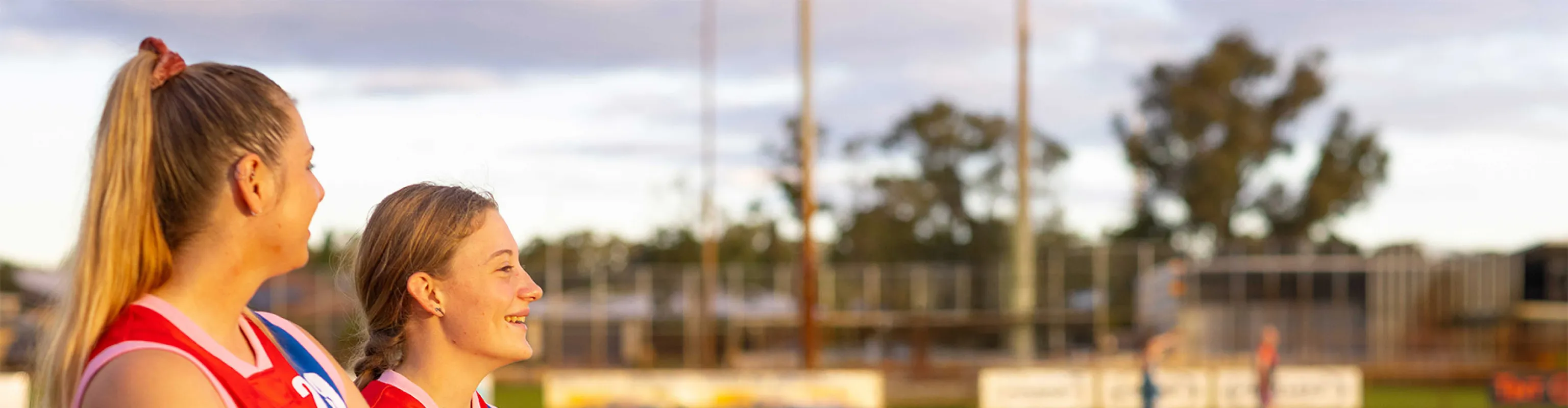 Two young women dressed in red and blu Australian football jerseys