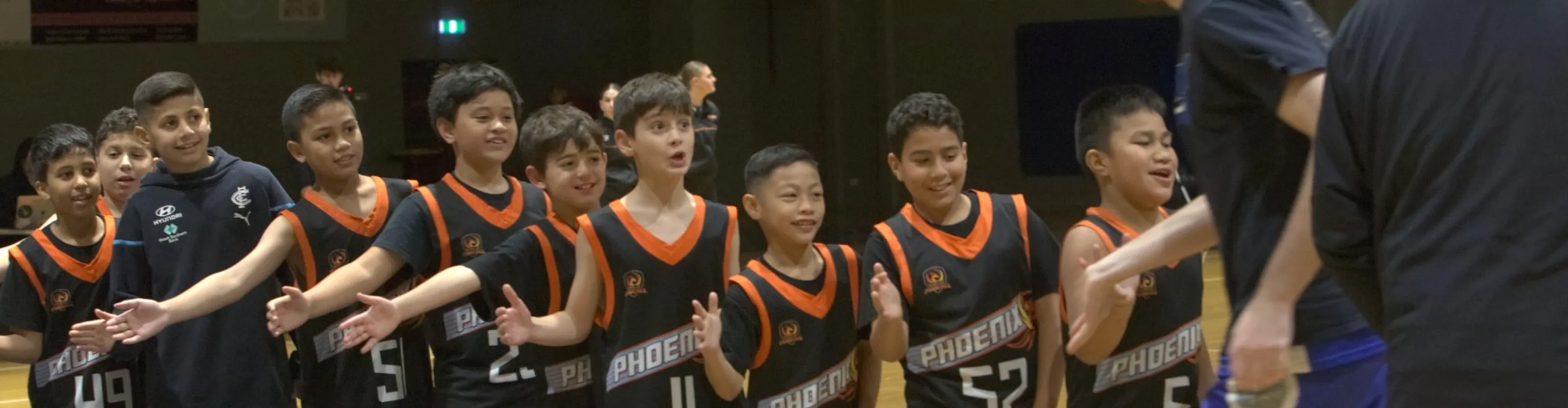 A junior Phoenix basketball team hold out their hands to give a passing coach a high-five