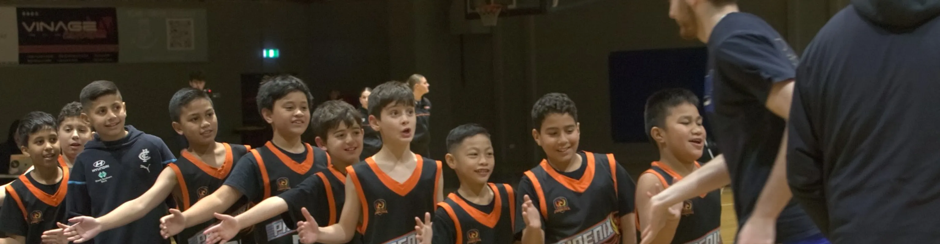 A junior Phoenix basketball team hold out their hands to give a passing coach a high-five