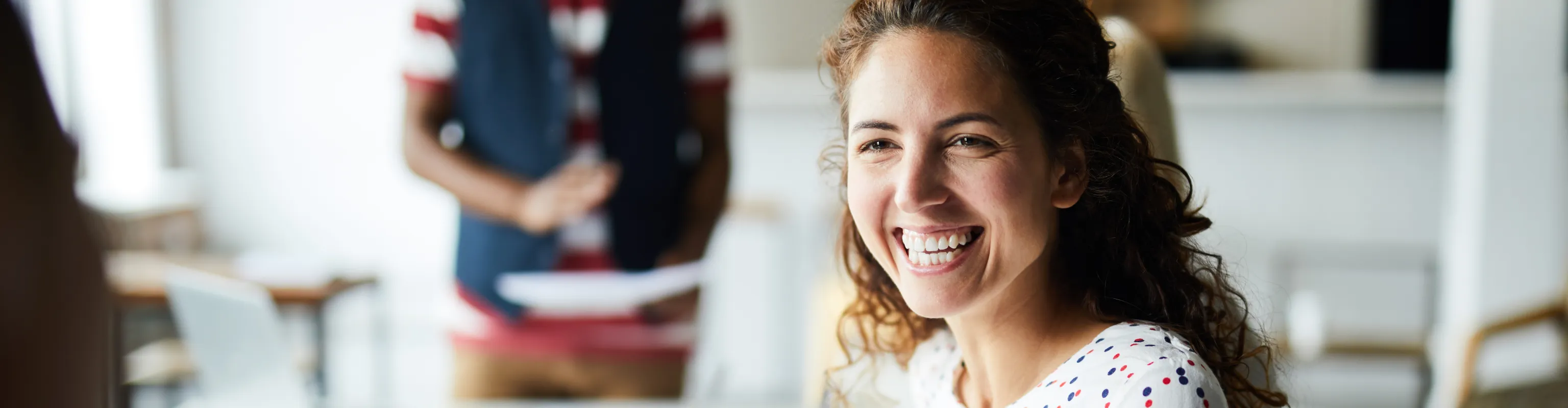 A woman smiles while chatting in a committee meeting