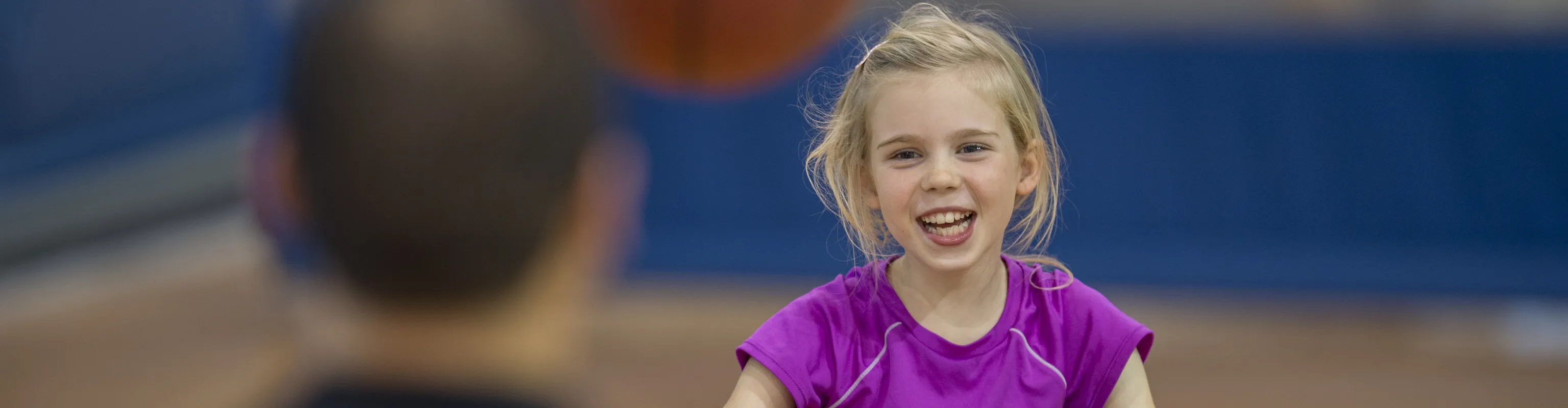 Young girl in a wheelchair throwing a basketball to a man