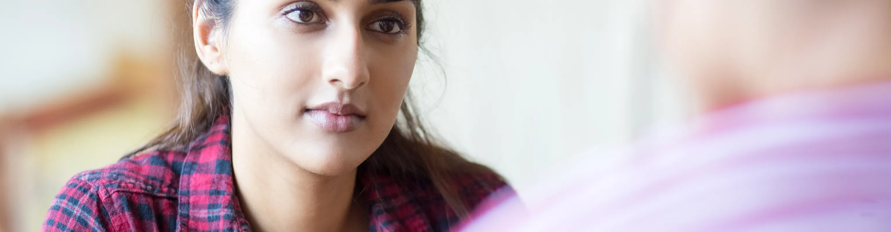 A woman with light brown skin and dark hair talks to someone 