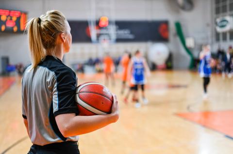 Basketball referee standing on side of court