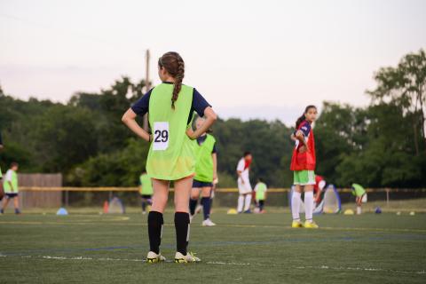 Teenage girls at football training stand on the playing field waiting for instruction