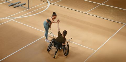A coach and wheelchair athlete high 5 each other