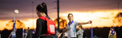 Young women playing netball in twilight