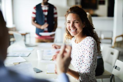 A woman smiles while chatting in a committee meeting
