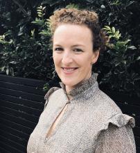 Photo of woman with curly hair smiling a camera