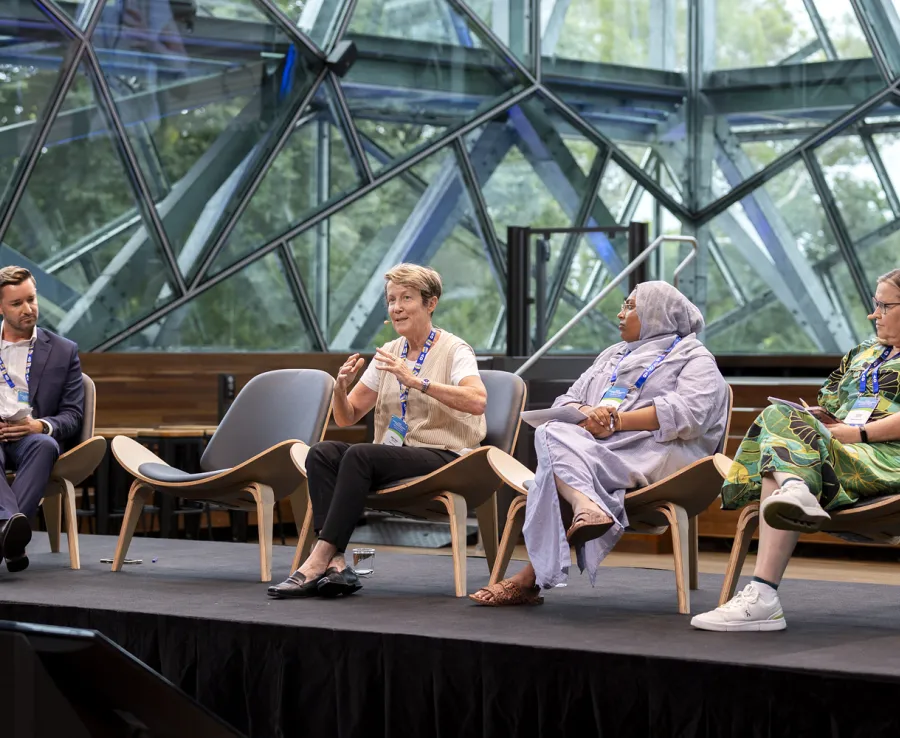 One man and three women take part in a panel discussino on a stage