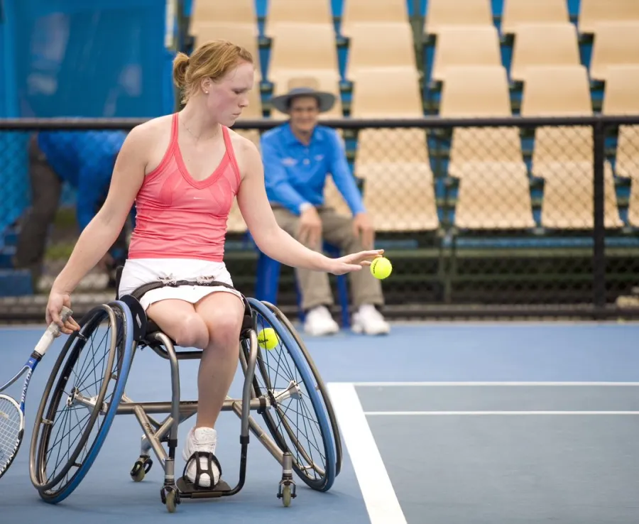 Woman in wheelchair serving a tennis ball