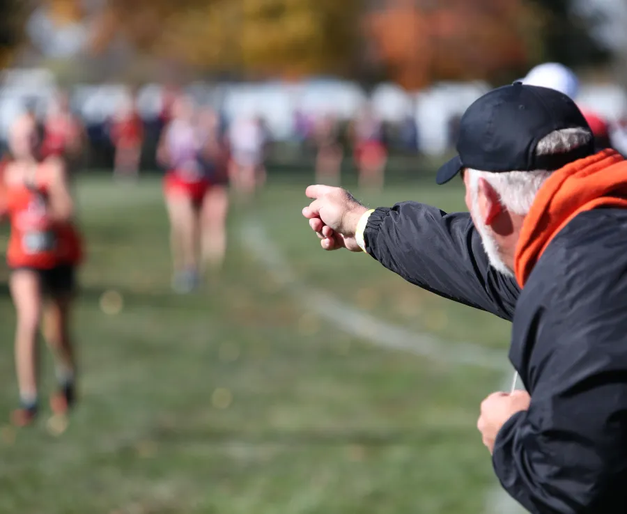 Man pointing at young athlete running