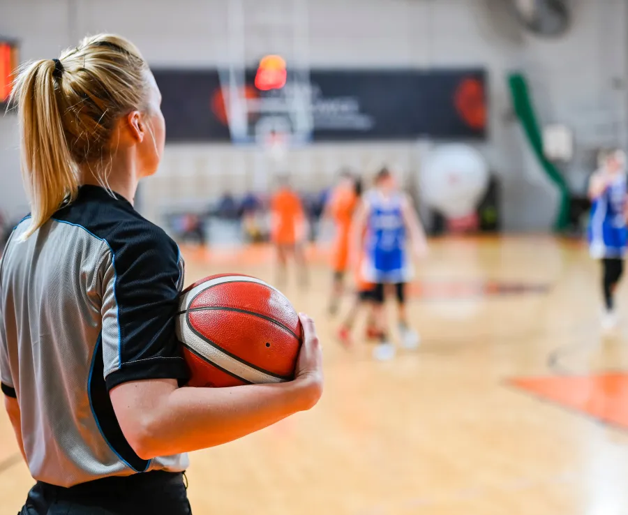 Basketball referee standing on side of court