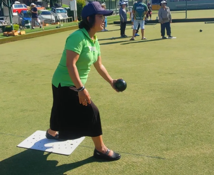 Woman in green top doing lawn bowls