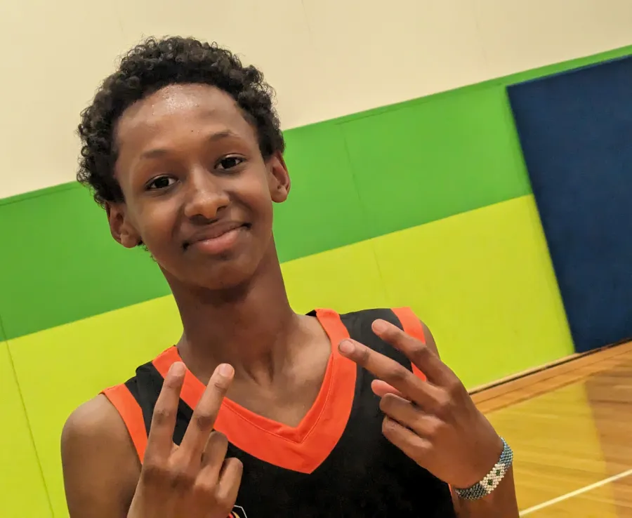 A young boy in a Phoenix jersey poses for the camera, holding up his hands in a Gen-Alpha style peace sign