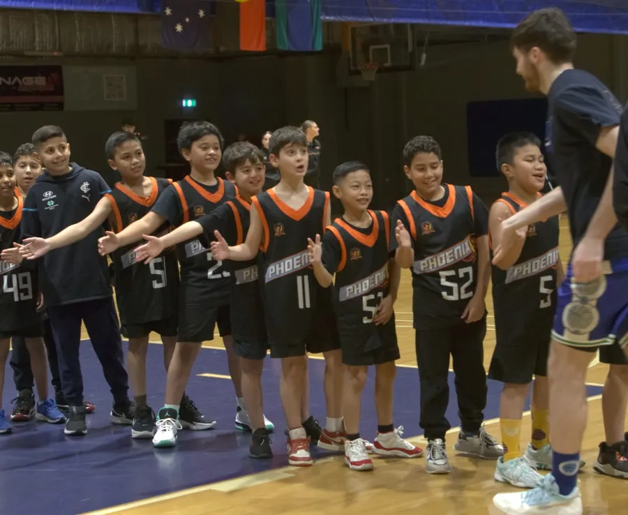 A junior Phoenix basketball team hold out their hands to give a passing coach a high-five