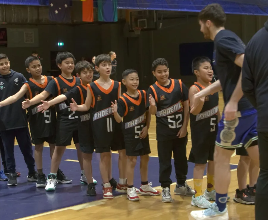 A junior Phoenix basketball team hold out their hands to give a passing coach a high-five