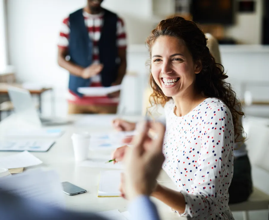A woman smiles while chatting in a committee meeting